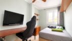Dormitorio juvenil del apartamento de playa en Palma con silla gaming, TV Sony, cama individual y ventilador de techo