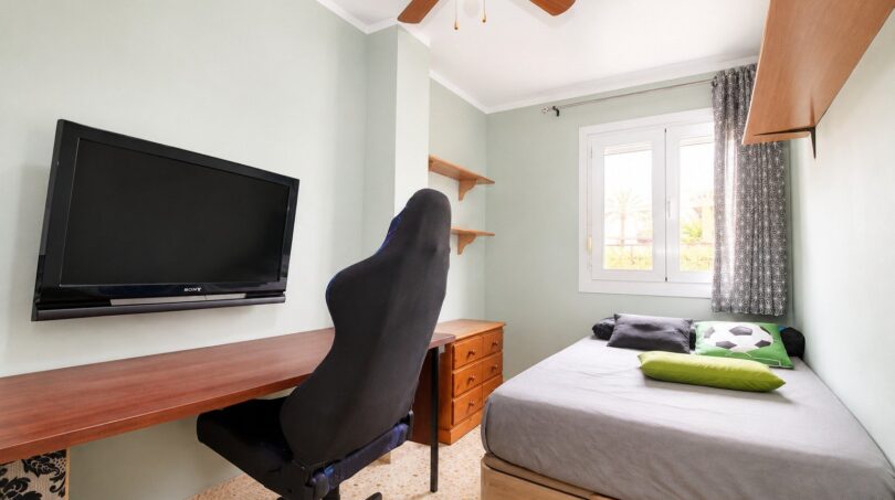 Dormitorio juvenil del apartamento de playa en Palma con silla gaming, TV Sony, cama individual y ventilador de techo