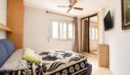 Dormitorio luminoso con cama doble, ventilador de techo, armario espejo y TV en vivienda de playa en Palma