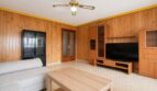 Salón con revestimiento de madera, ventilador de techo, mueble TV y sofá luminoso en Palma de Mallorca