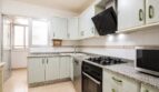 Cocina luminosa con armarios verde menta, encimera de granito, estufa de gas y microondas en vivienda de playa en Palma