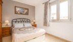 Dormitorio luminoso con cama doble, muebles de madera y ventana en vivienda cerca de la playa en Palma de Mallorca.