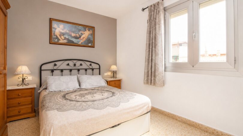 Dormitorio luminoso con cama doble, muebles de madera y ventana en vivienda cerca de la playa en Palma de Mallorca.