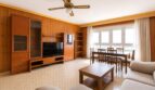 Luminosa sala de estar con revestimiento de madera, unidad de TV, mesa de comedor y vistas al mar cerca de la playa en Palma