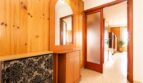 Entrada con revestimiento de madera, espejo, cómoda y puerta corredera en apartamento de playa en Palma de Mallorca