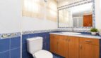 Baño con azulejos azules, mueble inferior de madera, espejo y cenefa decorativa en vivienda de playa en Palma
