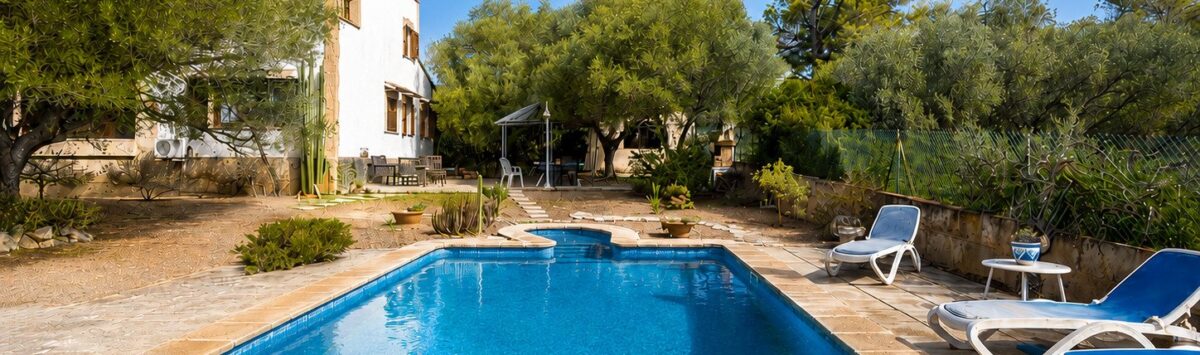 Außenpool mit Liegestühlen, weißer Finca und mediterranem Garten der Ferienvilla in Marratxí