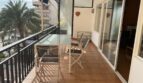Sonnige Terrasse mit Glastisch und Stühlen, Blick auf Palmen und Promenade, Wohnung am Paseo Marítimo Palma