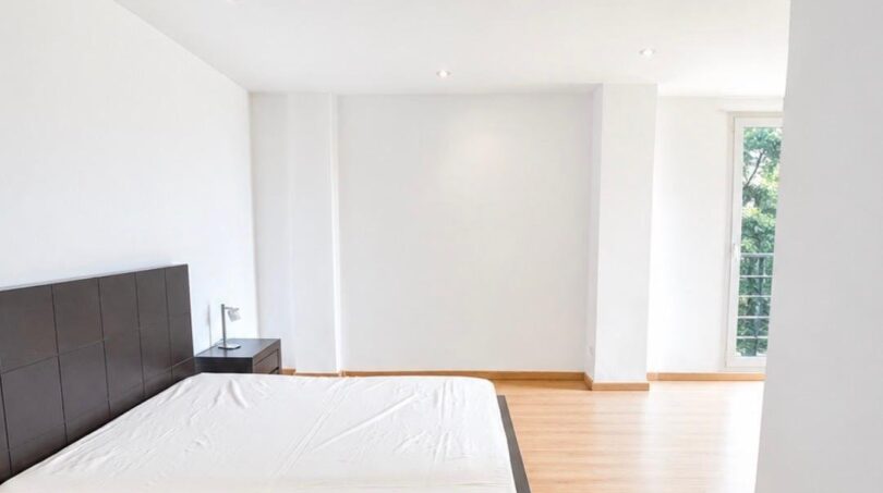 Helles Schlafzimmer mit dunklem Doppelbett, Parkettboden und großem Fenster in exklusiver Wohnung in Palma