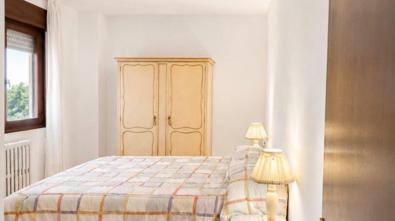 Helles Schlafzimmer der Luxuswohnung am Paseo Marítimo mit Doppelbett, Holzschrank und Parkettboden.