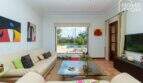 Helles Wohnzimmer der Villa in Lloseta mit Ledersofas, Terrakottaboden und Blick auf den Pool.