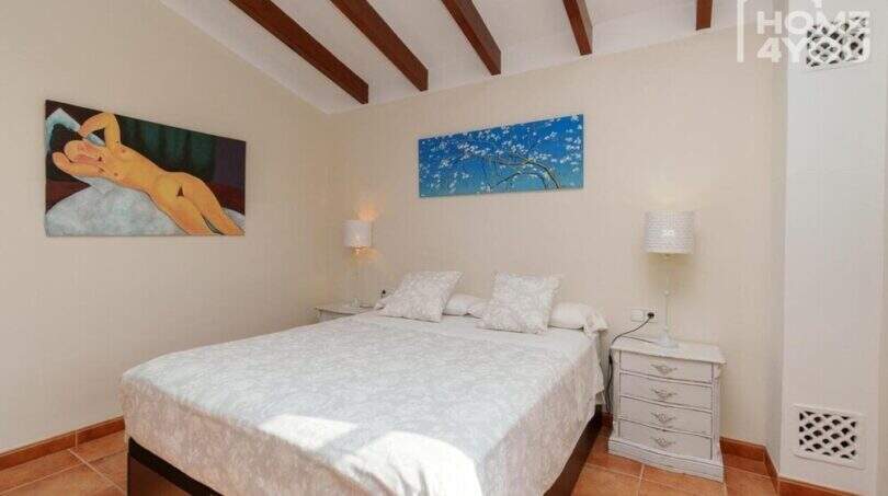 Helles Schlafzimmer der mallorquinischen Villa in Lloseta mit Doppelbett, Holzbalkendecke und mediterranem Flair.