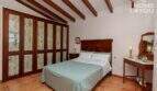 Schlafzimmer der mallorquinischen Villa in Lloseta mit Holzbalkendecke, Doppelbett und rustikalen Einbauschränken.