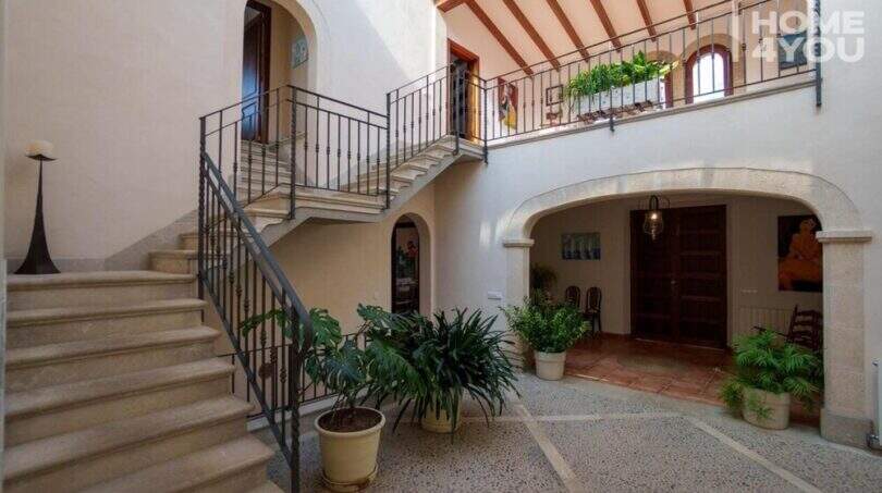 Innenhof der mallorquinischen Villa in Lloseta mit Steintreppe, Schmiedeisengeländer und mediterranen Pflanzen.