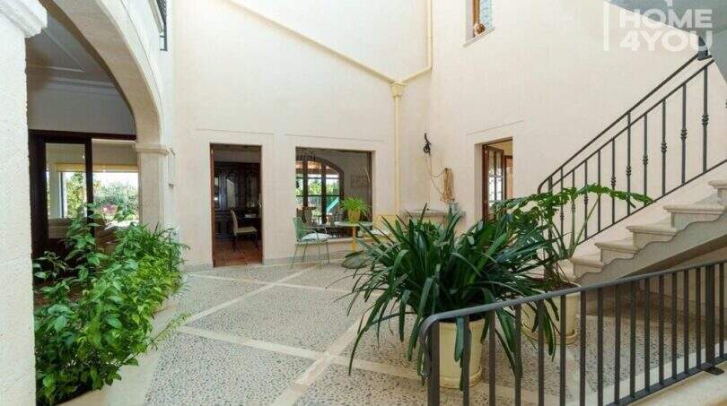 Eleganter Innenhof der mallorquinischen Villa in Lloseta mit Natursteinboden, Treppenaufgang und üppigen Grünpflanzen.