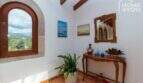 Eingangsbereich der mallorquinischen Villa mit Rundbogenfenster, Holzbalken, Konsolentisch und Tramuntana-Blick