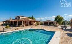 Mediterrane Finca in Santa Margalida: Außenansicht mit Pool, Terrasse und Garage bei blauem Himmel.