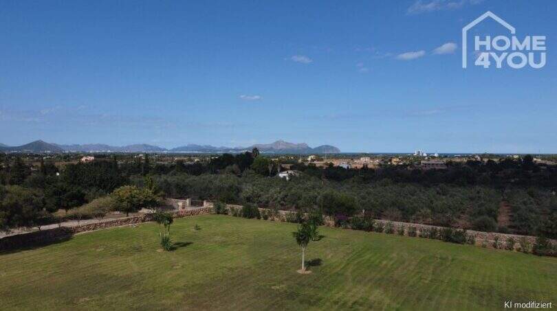 Extenso jardín de la finca en Santa Margalida con palmeras, muros de piedra y panorama montañoso al fondo.