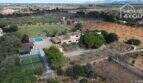 Vista aérea finca mediterránea Santa Margalida: casa principal, piscina, pista de pádel, jardín en 8.970 m² con vista a las montañas.