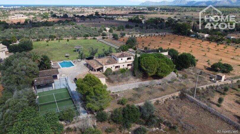Vista aérea finca mediterránea Santa Margalida: casa principal, piscina, pista de pádel, jardín en 8.970 m² con vista a las montañas.