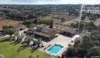 Vista aérea finca mediterránea Santa Margalida: piscina, pista de pádel, área de jardín y edificios auxiliares en 8.970 m²