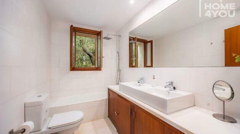 Helles Badezimmer der Finca mit Doppelwaschbecken, Badewanne, Dusche und Holzakzenten in Campanet.