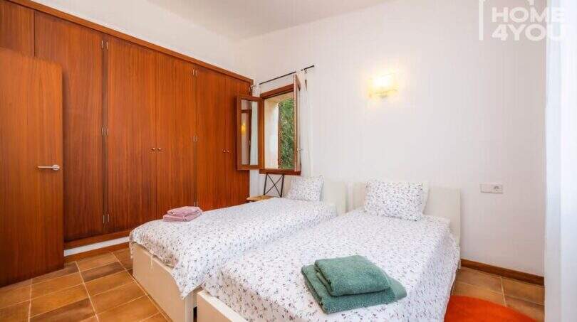 Schlafzimmer der Finca Campanet mit zwei Einzelbetten, großem Holzschrank und Terrakottaboden