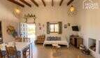 Living area of Finca Felanitx with wooden beam ceiling, fireplace, dining table and lounge area with TV
