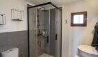 Modern bathroom of Finca Felanitx with glass shower, toilet and sink, gray tile accents.