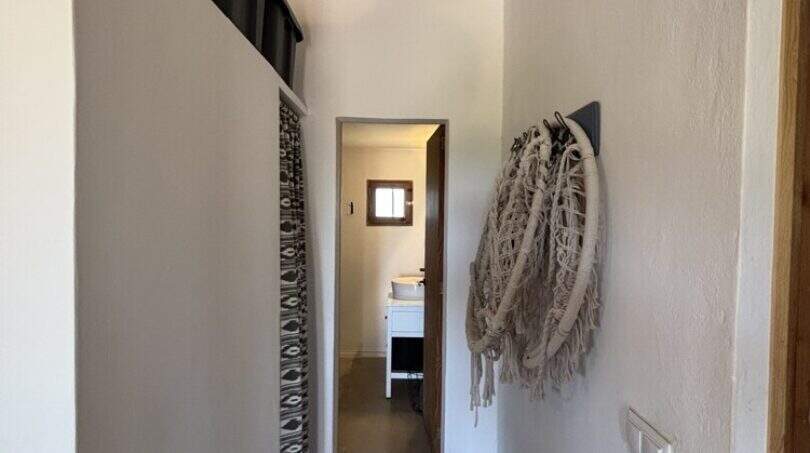 Narrow hallway with wooden beam ceiling, leading to bathroom, wardrobe with macramé wall decoration, Finca Felanitx