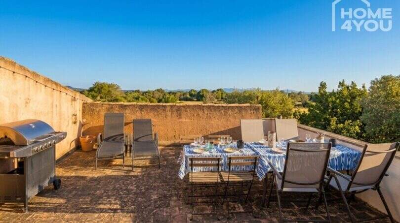 Sunny roof terrace of the finca near Felanitx with dining table, sun loungers, grill and panoramic view of the countryside.