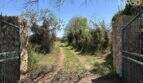Rustic natural stone entrance gate with iron fence and unpaved access road to the finca near Felanitx
