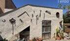 Rustic outbuilding of Finca Felanitx with wooden door, antique tools, cacti and Mediterranean charm.