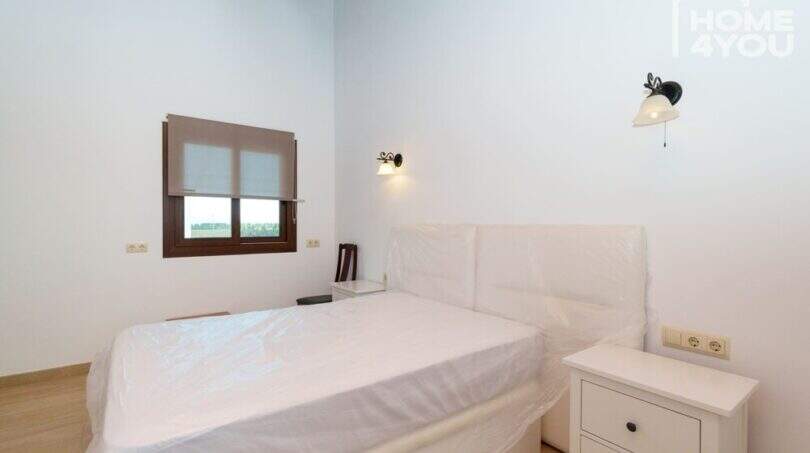 Helles Schlafzimmer der Finca in Santa Margalida mit Doppelbett, Wandleuchten und Holzboden.