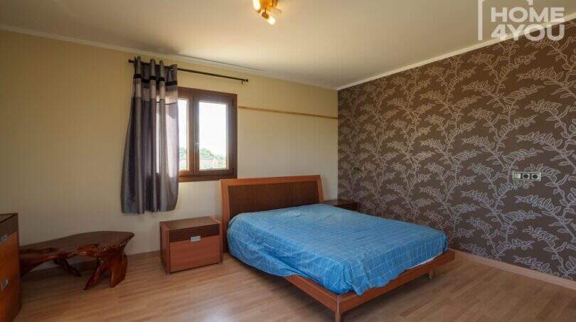 Schlafzimmer mit Doppelbett, Holzboden, dekorativer Tapetenwand und Fenster in moderner Finca, Santa Margalida