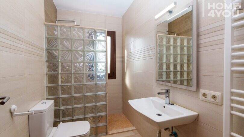 Helles Badezimmer der Finca mit Glasbausteindusche, WC, Waschtisch und Handtuchheizkörper.