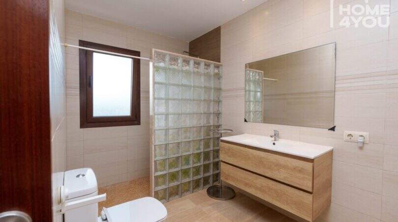 Modernes Badezimmer der Finca in Santa Margalida mit Glasbausteindusche, Holzwaschtisch und großem Spiegel.
