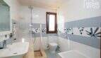 Helles Badezimmer der Finca mit Dusche, Badewanne, WC und blau-weißen Blumenfliesen.