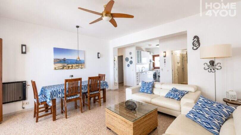 Luminosa sala de estar con comedor, ventilador de techo, decoración marina y cocina abierta – Apartamento en Ses Salines, a 80 m del mar.