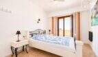 Luminoso dormitorio con cama doble, ventilador de techo y balcón con vista al mar en apartamento en Ses Salines.
