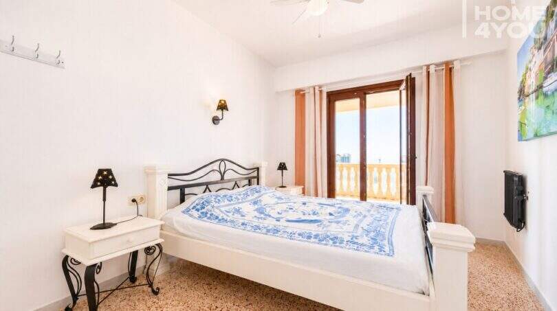 Luminoso dormitorio con cama doble, ventilador de techo y balcón con vista al mar en apartamento en Ses Salines.