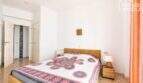 Luminoso dormitorio con cama doble, muebles de ratán y colcha multicolor en apartamento con vista al mar en Ses Salines.