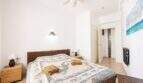 Luminoso dormitorio con cama doble, muebles de ratán, ventilador de techo y obra de arte con vista al mar en apartamento Ses Salines.