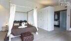 Dormitorio elegante con cama con dosel, decoración de bambú, baño en suite y vista panorámica en finca mediterránea Sa Pobla