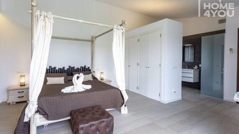 Dormitorio elegante con cama con dosel, decoración de bambú, baño en suite y vista panorámica en finca mediterránea Sa Pobla
