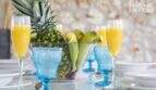 Finca mediterránea: mesa cubierta con frutero, vasos azules y zumo de naranja fresco