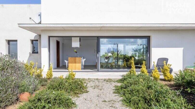 Finca moderna en Sa Pobla: bungalow de techo plano con gran frente de cristal, terraza y jardín mediterráneo
