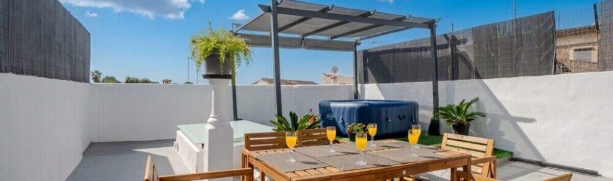 Dachterrasse mit Holzmöbeln, Jacuzzi unter Pergola und Orangensaftgläsern, Stadthaus Maria de la Salut