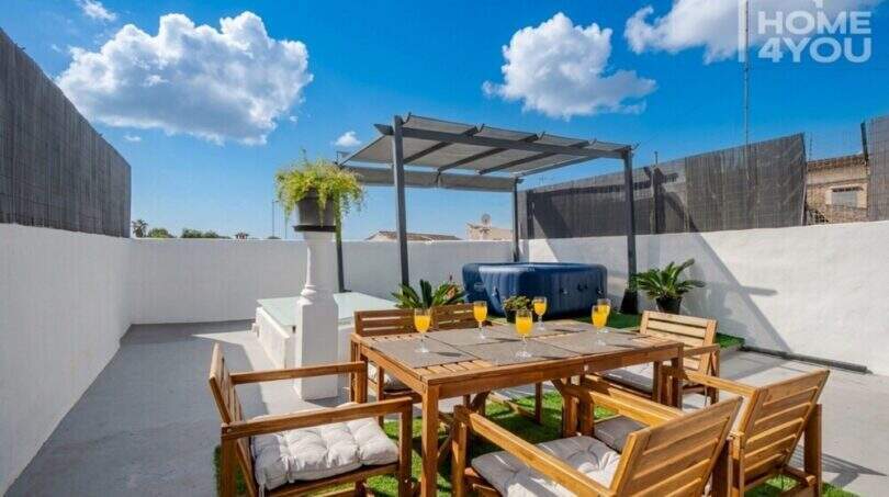 Dachterrasse mit Holzmöbeln, Jacuzzi unter Pergola und Orangensaftgläsern, Stadthaus Maria de la Salut