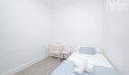 Helles Schlafzimmer mit Einzelbett, mintfarbener Bettwäsche, weißem Nachttisch und hellem Holzboden im Stadthaus Maria de la Salut